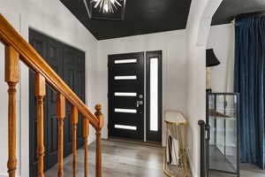 Entrance foyer with light wood-style flooring and vaulted ceiling