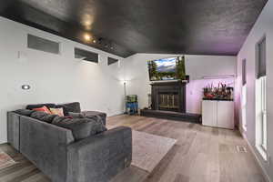 Living area featuring rail lighting, light wood-style floors, and a brick fireplace