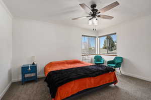 Bedroom with dark carpet, ceiling fan, and crown molding