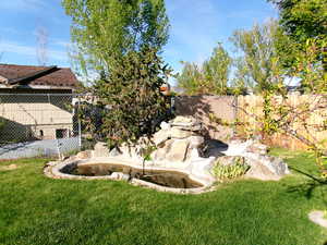 Fenced backyard featuring a small pond with waterfall