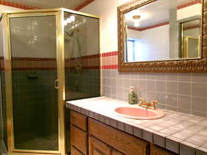Basement 3/4 Bathroom featuring backsplash, vanity, a shower stall, and tile walls