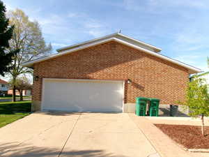 View of south side of property with brick siding, a 2 car garage, and driveway