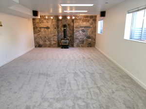 Unfurnished living room with a wood stove, light carpet, and rail lighting