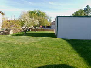 View of east side of yard featuring fruit trees and an outbuilding