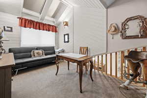 Office area featuring wooden walls, carpet flooring, and vaulted ceiling with beams