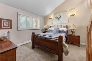Bedroom with vaulted ceiling and light carpet