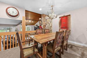 Dining space featuring carpet flooring, suspended lighting, and a vaulted wooden ceiling