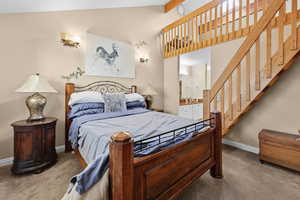 Bedroom featuring lofted ceiling with beams, carpet, and ensuite bathroom