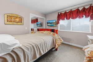 Carpeted bedroom featuring a closet and baseboards