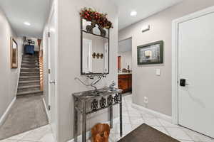 Hall with light tile patterned floors, recessed lighting, and light colored carpet