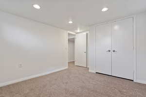Unfurnished bedroom with light colored carpet, recessed lighting, and a closet