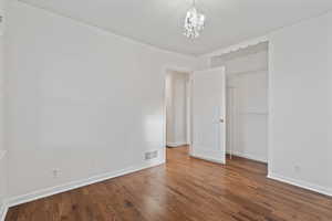 Unfurnished bedroom featuring dark wood-type flooring, a closet, and a chandelier