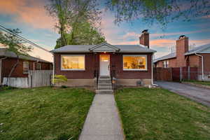 Bungalow-style home with brick siding, a chimney, and entry steps