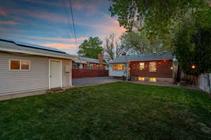 Back of property with a patio, a fenced backyard, and roof mounted solar panels