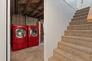 Laundry area with unfinished concrete flooring and washer and clothes dryer