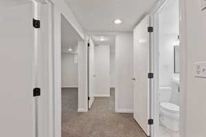 Corridor featuring light carpet, recessed lighting, and a textured ceiling