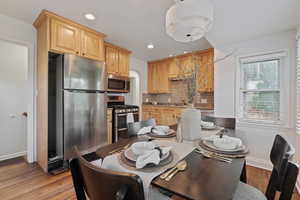 Dining room with recessed lighting, arched walkways, and light wood-style flooring