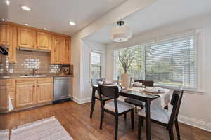 Kitchen with stainless steel dishwasher, light wood finish cabinets, wood-type flooring, recessed lighting, and tasteful backsplash