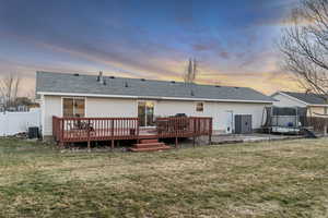 Back of property with a fenced backyard, a trampoline, a shingled roof, and a deck