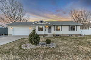 Single story home featuring an attached garage, roof with shingles, driveway, and a gate