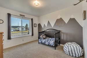 Carpeted bedroom with baseboards and a crib