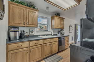 Kitchen with dark countertops, stainless steel appliances, light wood-style floors, and wood finish cabinetry