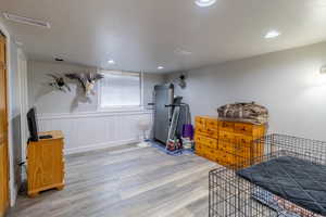 Bedroom featuring light wood-type flooring, a wainscoted wall, and recessed lighting