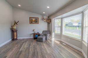 Living area with vaulted ceiling, light wood-style flooring, and recessed lighting
