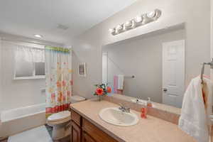 Bathroom with vanity, shower / bathtub combination with curtain, and recessed lighting
