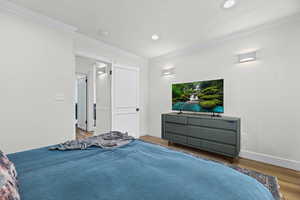 Bedroom with crown molding, wood finished floors, and recessed lighting