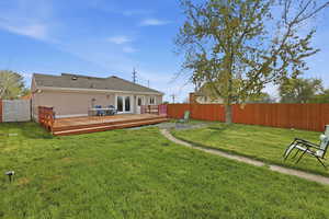 Rear view of house with a fenced backyard, stucco siding, a deck, and french doors