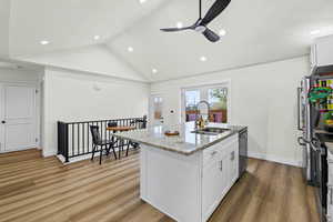 Kitchen featuring white cabinetry, ceiling fan, light stone counters, an island with sink, and recessed lighting