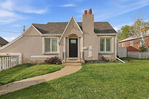 Tudor home featuring stucco siding, a chimney, and roof with shingles