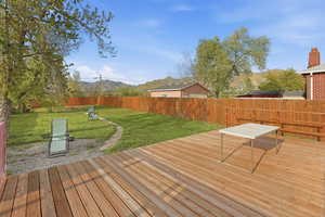 Wooden deck with a fenced backyard and a mountain view
