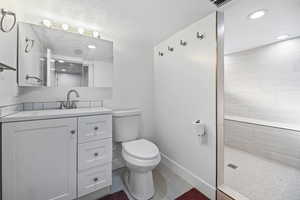 Full bath with vanity, walk in shower, and a textured ceiling