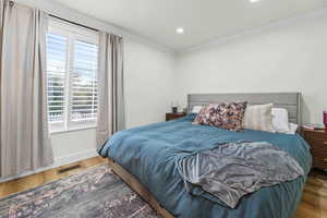 Bedroom with wood finished floors, ornamental molding, and recessed lighting