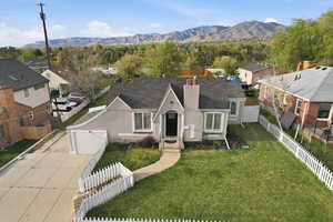 View of front of house with concrete driveway, stucco siding, a fenced front yard, a chimney, and a mountain view