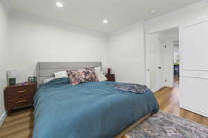 Bedroom featuring light wood finished floors, crown molding, and recessed lighting