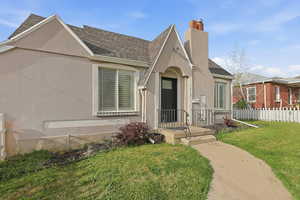 View of front of property with stucco siding, a shingled roof, and a chimney