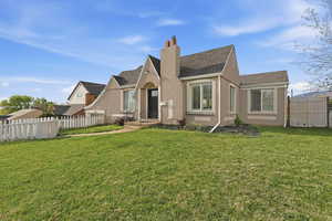 Tudor-style house featuring a chimney, a shingled roof, and stucco siding