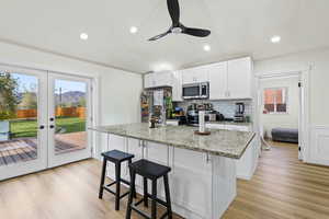 Kitchen featuring a center island with sink, white cabinetry, a breakfast bar area, light wood-type flooring, and a mountain view