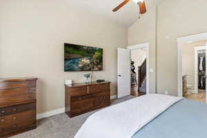 Primary Bedroom with lofted ceiling, light carpet, ensuite bath, and a ceiling fan