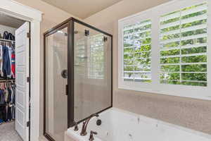 Master Bathroom with a walk in closet, a shower stall, and a whirlpool tub