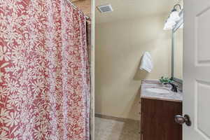 Bathroom featuring vanity, a shower with curtain, light tile patterned flooring, and a textured ceiling