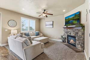 Living area featuring a ceiling fan, a stone fireplace, and recessed lighting