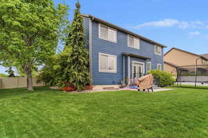 Rear view of house with a fenced backyard, a trampoline, and a patio