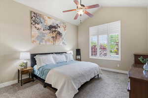 Primary Bedroom featuring vaulted ceiling, light carpet, and a ceiling fan