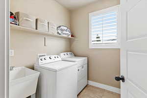 Laundry area with washing machine and dryer and light tile patterned flooring