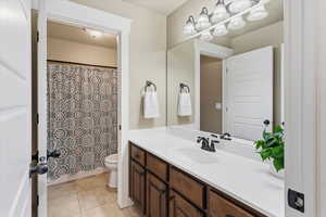 Full bathroom with vanity, light tile patterned floors, and shower / bath combo with shower curtain