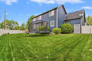 Rear view of house featuring a fenced backyard and a trampoline